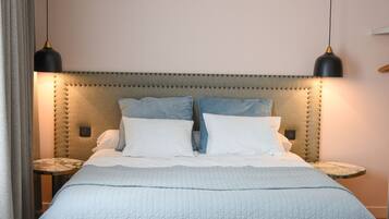 A neatly made bed with a quilted cover, two bedside tables with lamps, and a tufted headboard.