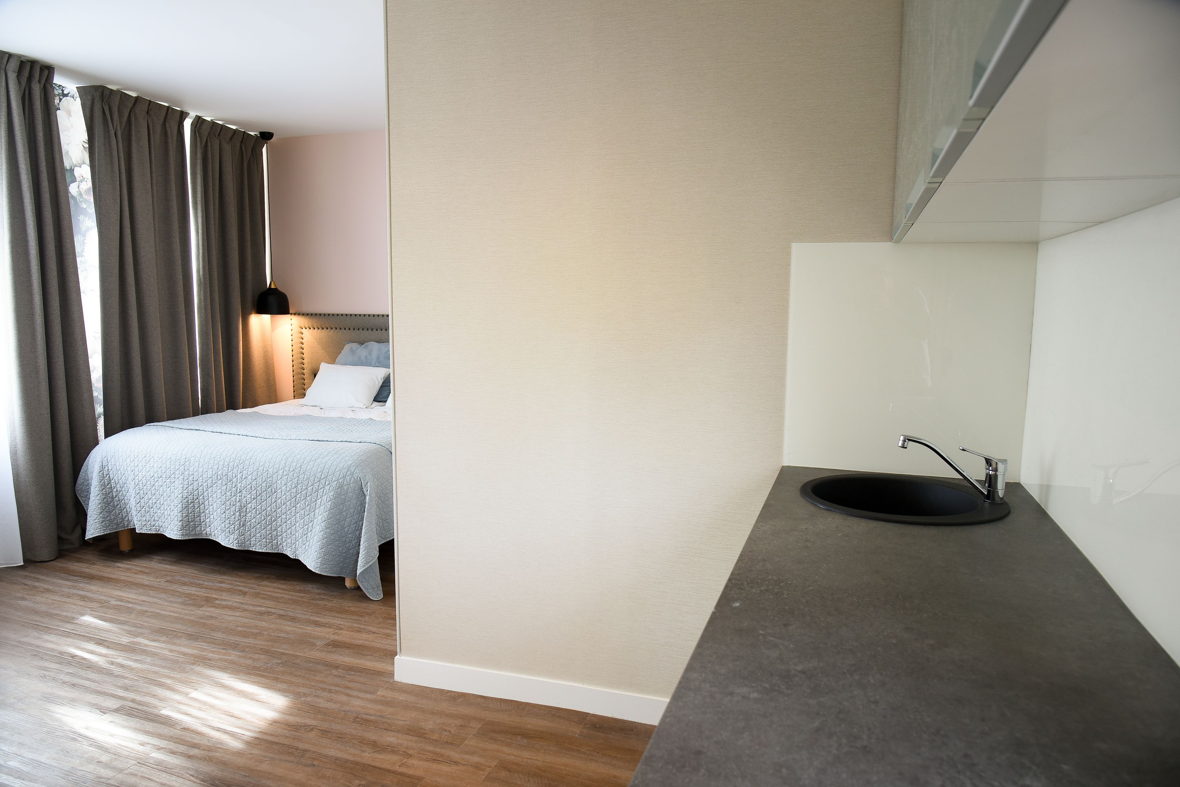 A bedroom with a bed, bedside lamp, and a bathroom with a sink and mirror.