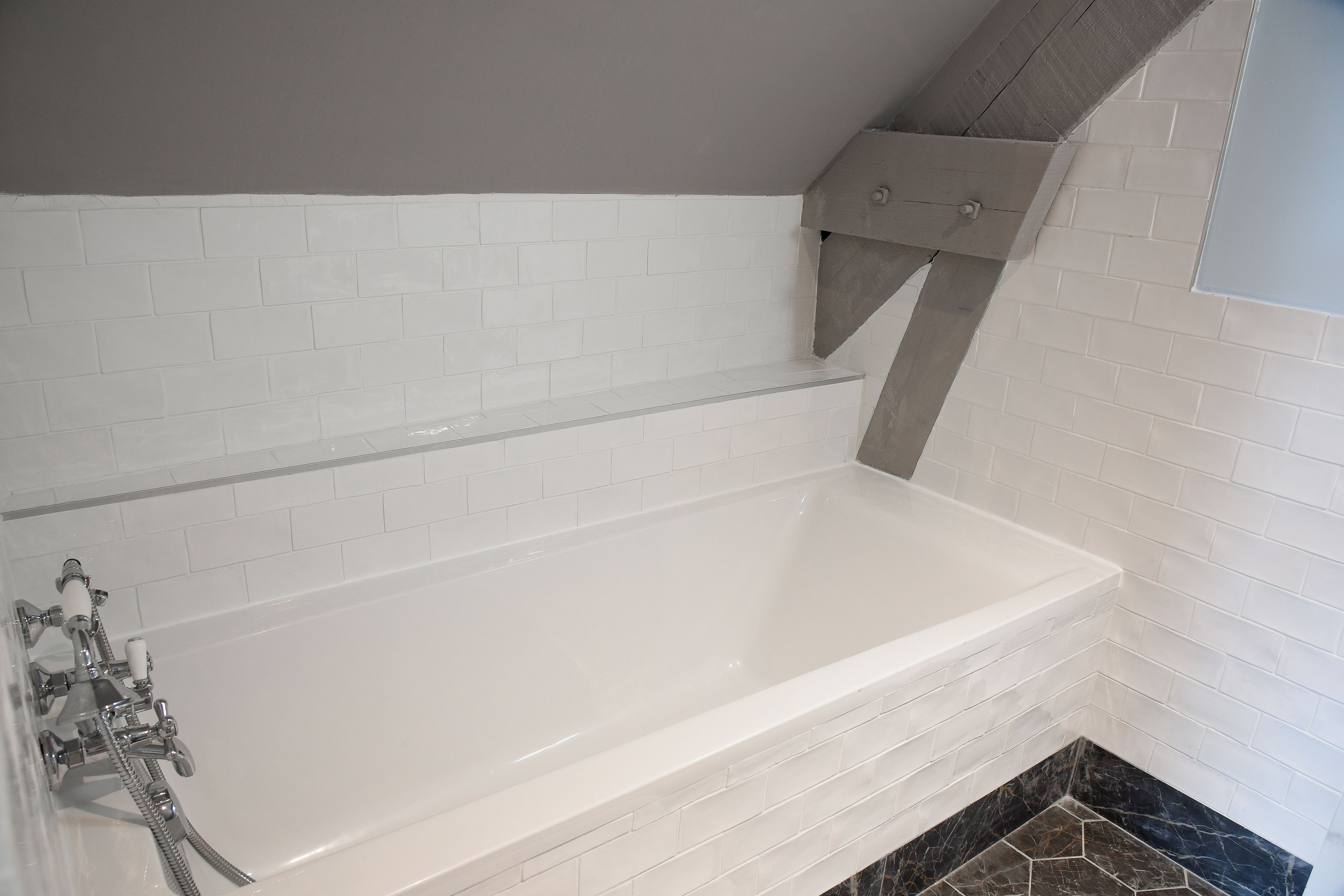 Une salle de bain moderne avec une baignoire blanche, un plafond gris et un espace douche d’angle.