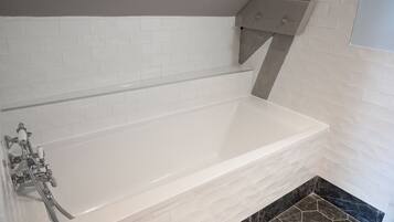 Une salle de bain moderne avec une baignoire blanche, un plafond gris et un espace douche d’angle.
