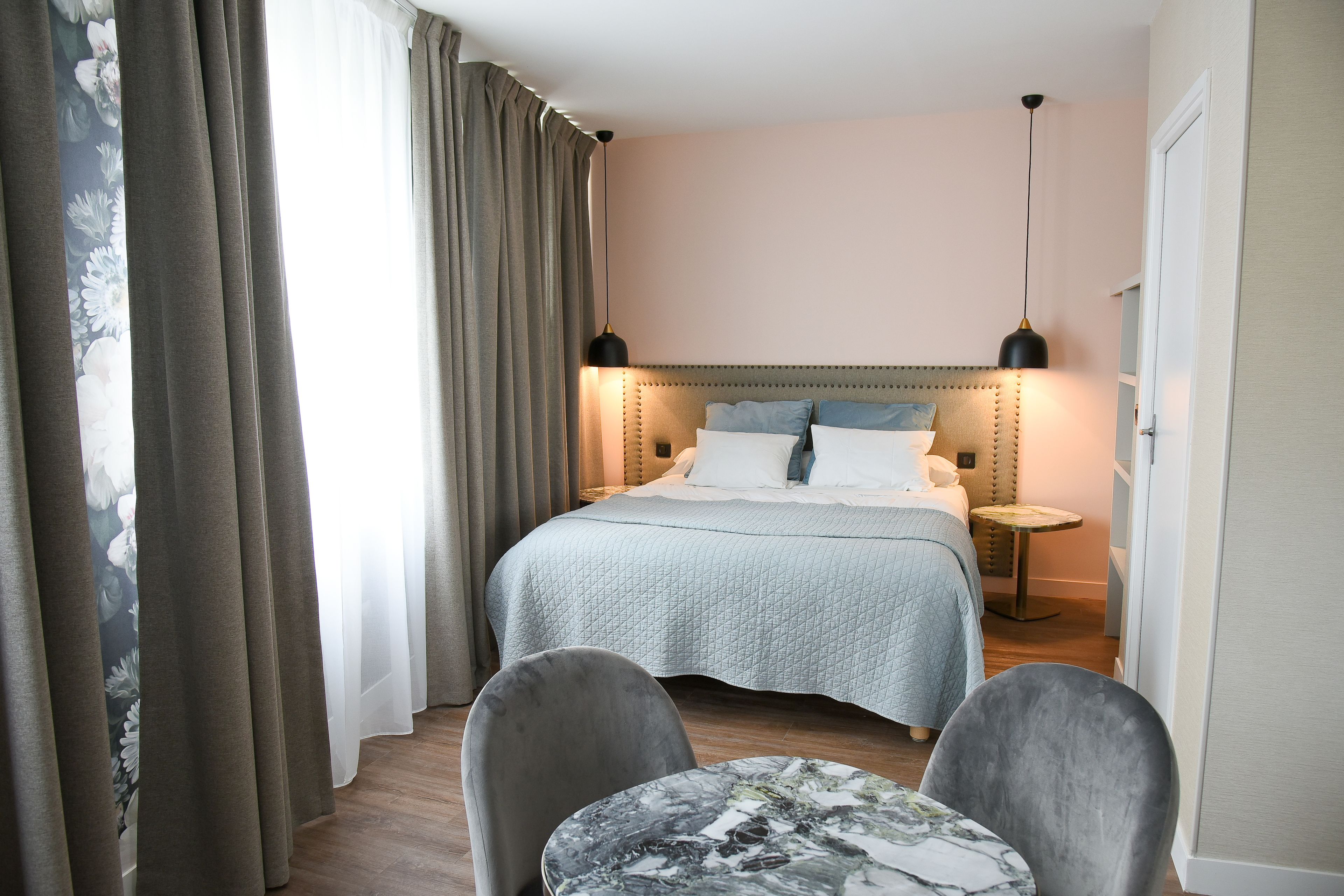 Une chambre d’hôtel comprenant un lit, deux tables de chevet, une table ronde et deux chaises.