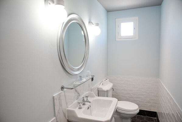 Une salle de bain avec un lavabo blanc, des toilettes et un miroir.