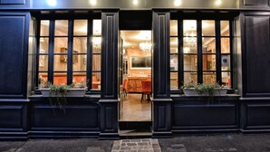 A building entrance with large windows, potted plants, and a chandelier visible inside. - Auberge la Renaissance (Viarmes)