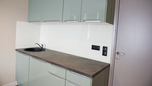 A kitchen with a sink, cabinets, and a door. - Auberge la Renaissance (Viarmes)