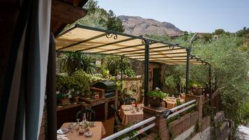 An outdoor patio with tables and chairs, a grill, and potted plants.