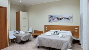 A hotel room with two beds, a wooden wardrobe, a desk, and a chair. - B&B Panorama (Castelbuono)