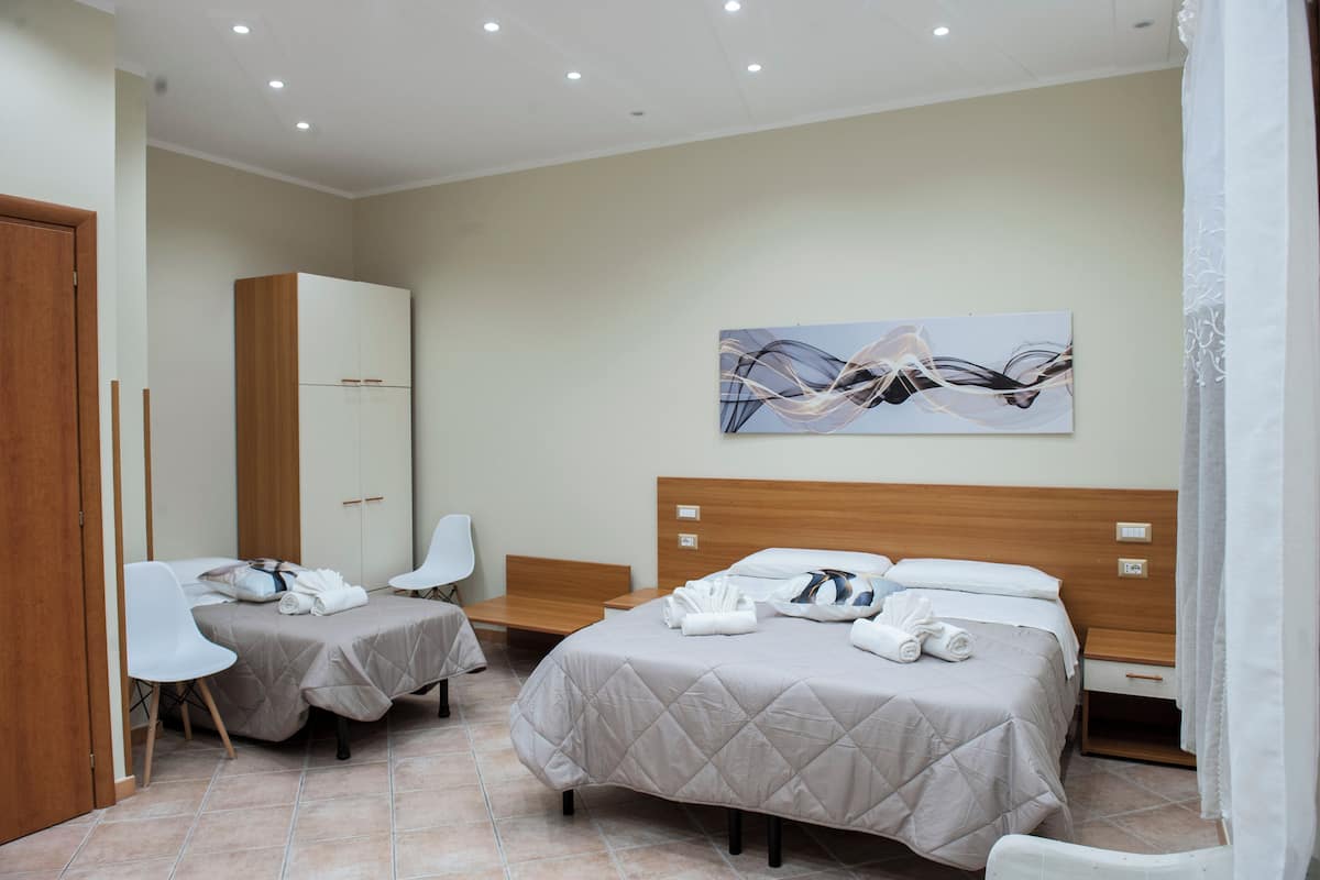 Habitación de hotel con dos camas, un armario de madera, un escritorio y una silla.
