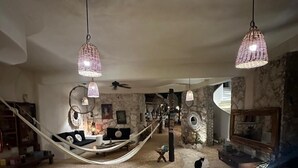 Een ruime woonruimte met een hangmat, stenen muren en hangende lampen.