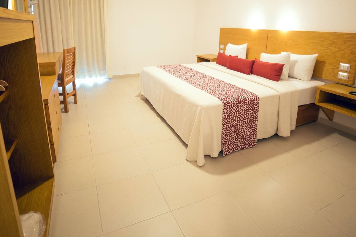 Ein Hotelzimmer mit einem Bett, Nachttischen, einem Holztisch und einem Sessel.