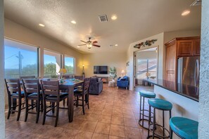 A spacious living area with a dining table, chairs, a sofa, and a kitchen area with a refrigerator. - At Canyon Lake CL1233 3 Bedroom Villa by RedAwning (Canyon Lake)