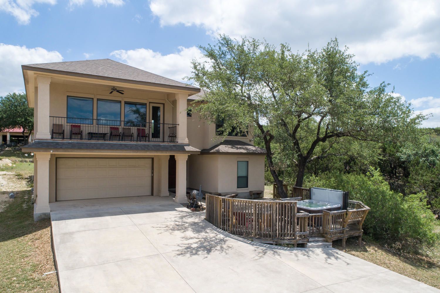 A two-story house with a garage, a balcony, and a hot tub area.