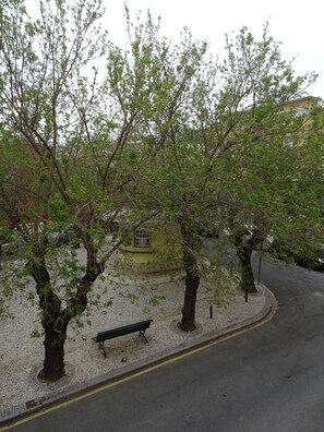 A paved pathway with a bench, trees, and a building in the background. - Guest House do Largo (Faro)