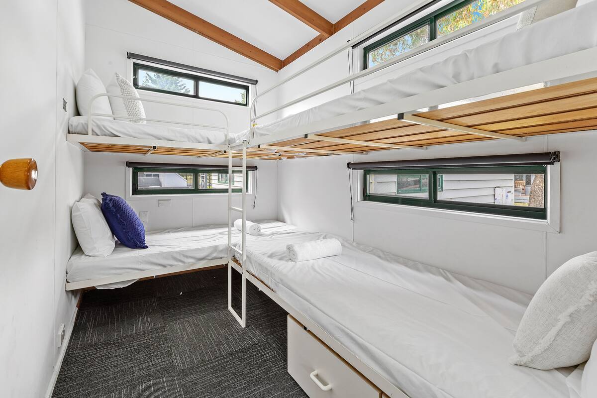 A compact, well-lit room with bunk beds, a small window, and a door.