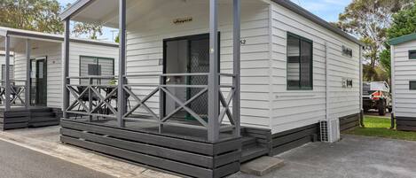 A mobile home with a covered porch, a small front entrance, and a number "62" on the side.