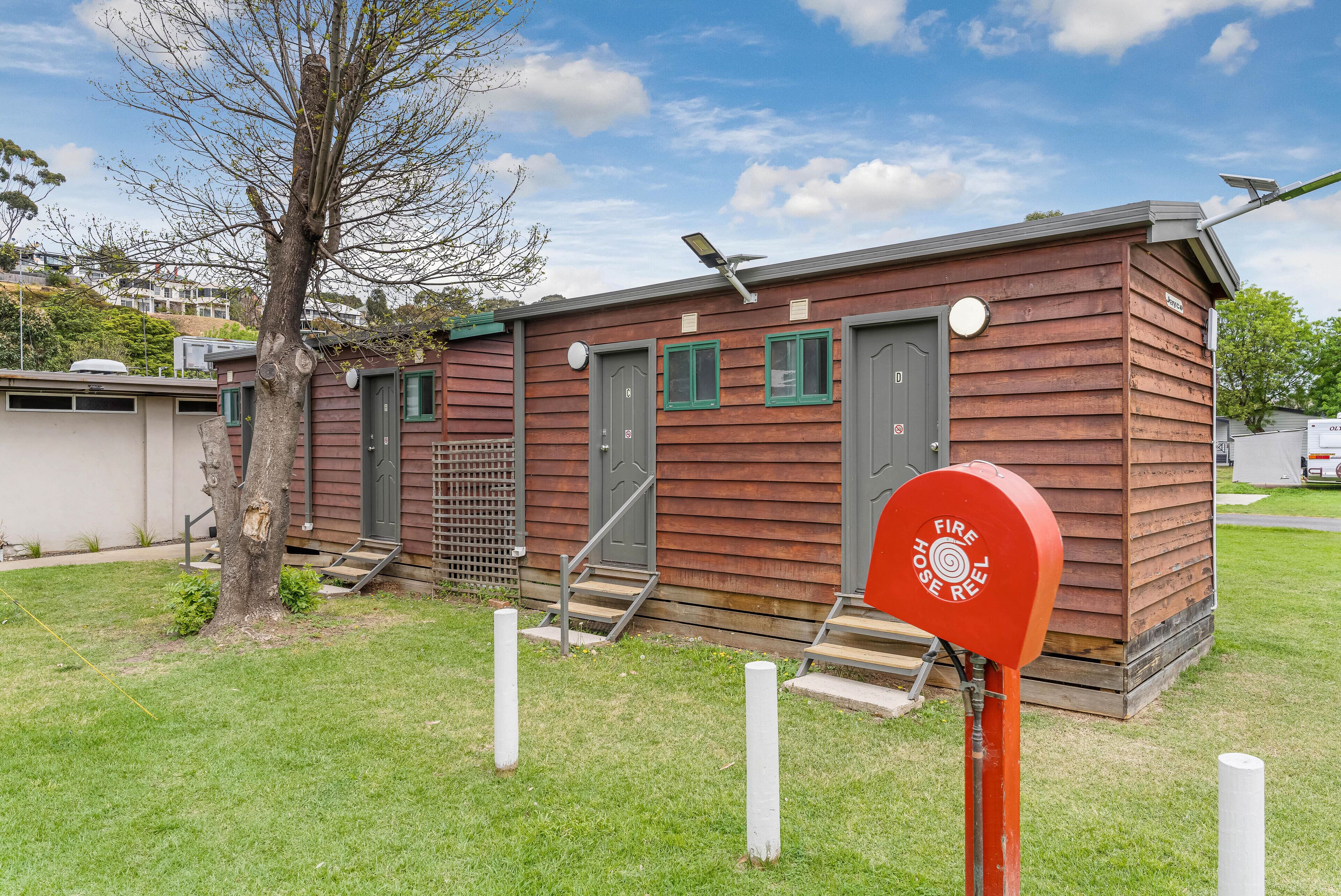 A small wooden building with two doors and a fire hose reel.