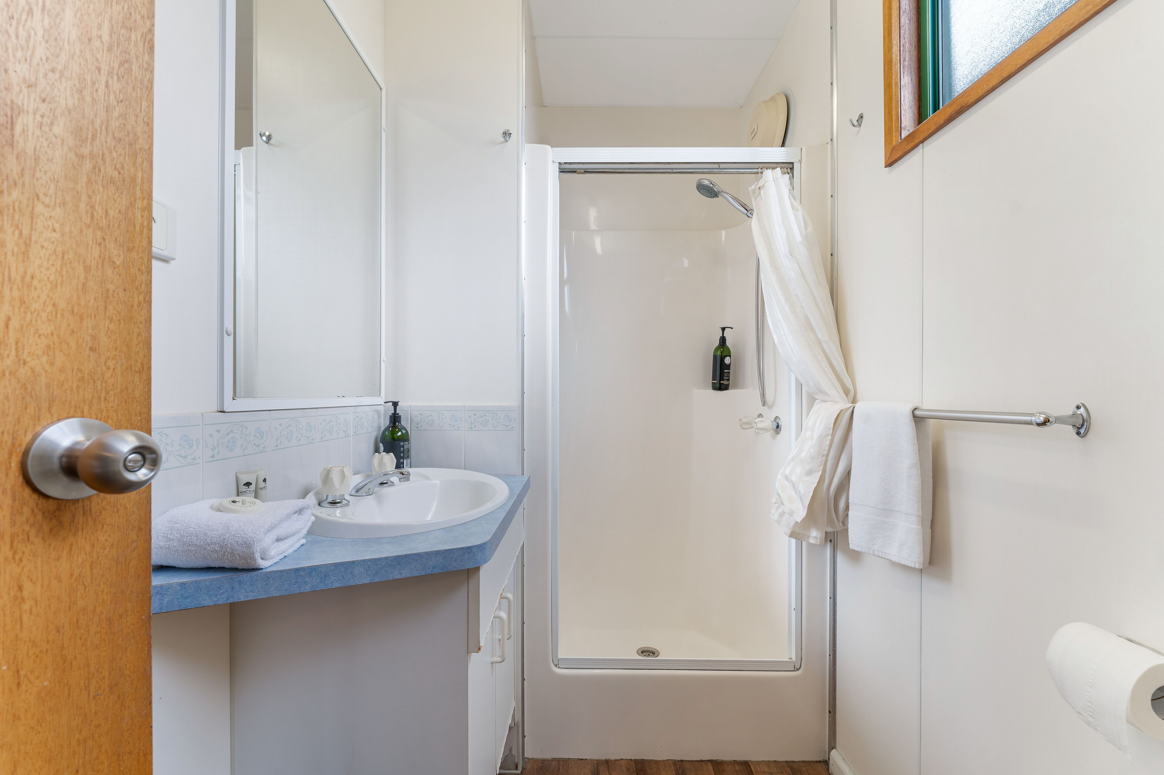 A bathroom with a shower, sink, and mirror.