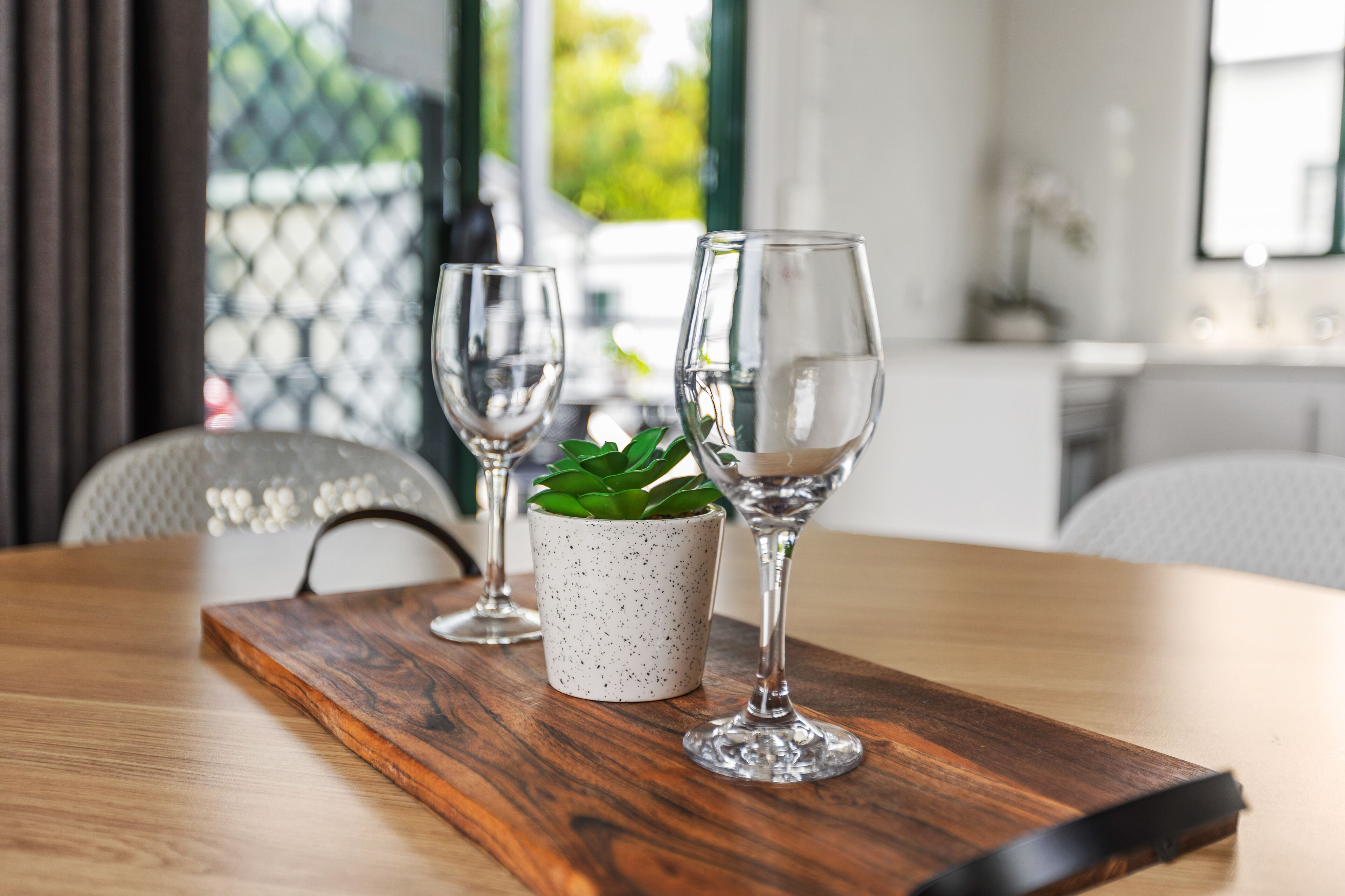 Una mesa de madera con dos copas de vino y una pequeña planta en maceta.