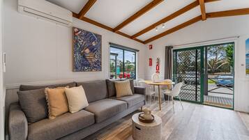 A modern living room with a grey sofa, a round coffee table, and a large window with a view of the outside.
