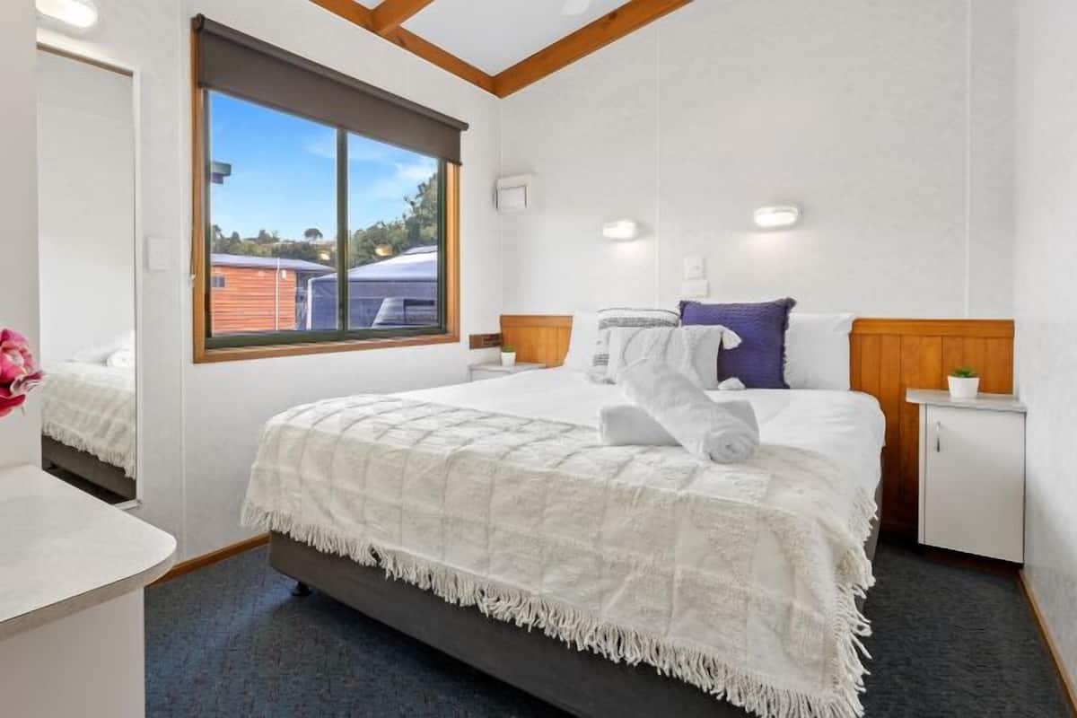A hotel room with a large bed, a window with a view, a bedside table, and a nightstand.