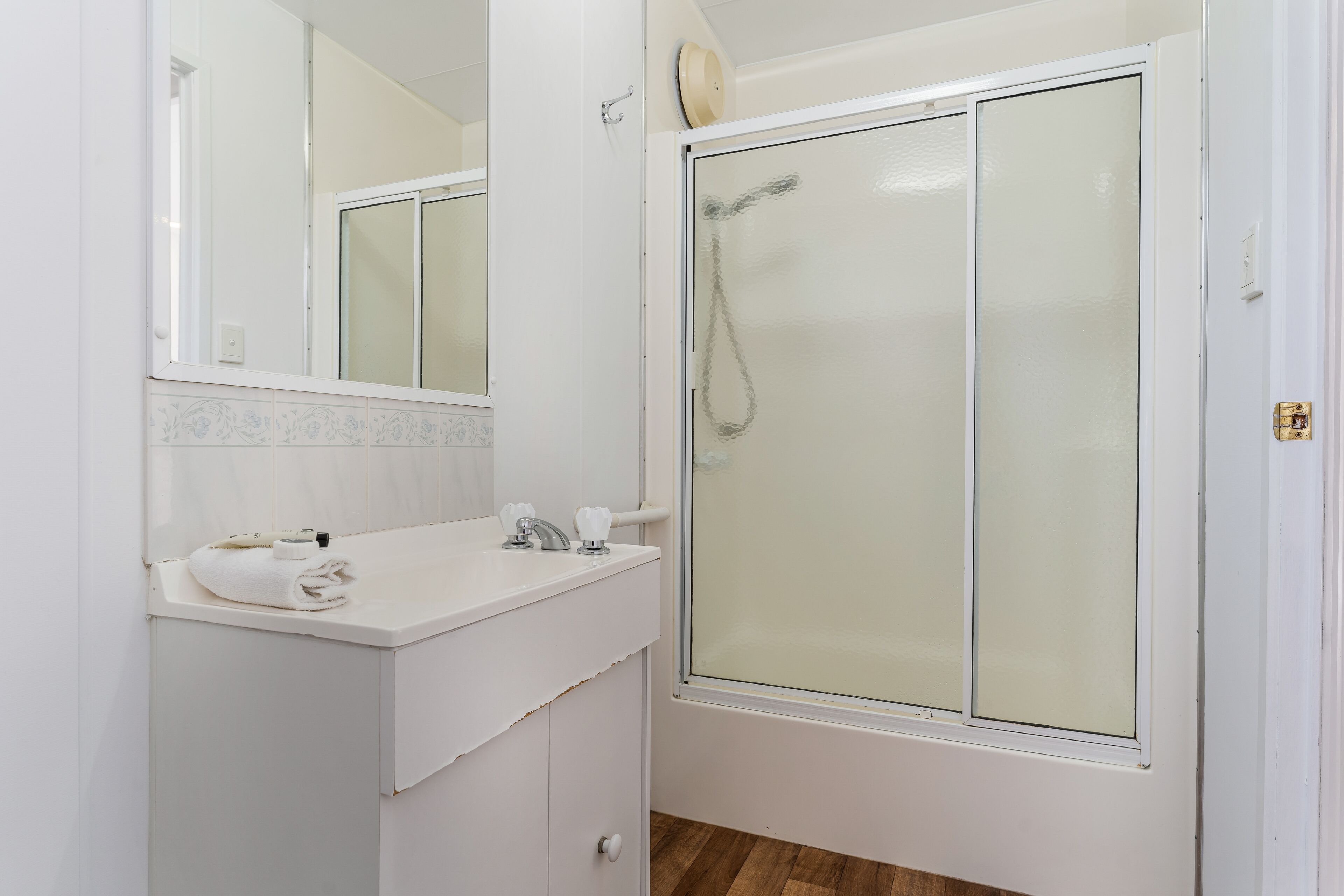A bathroom with a white sink, a mirror, and a shower enclosure.