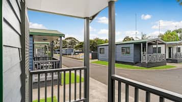 A row of mobile homes with a covered porch and a grassy lawn.