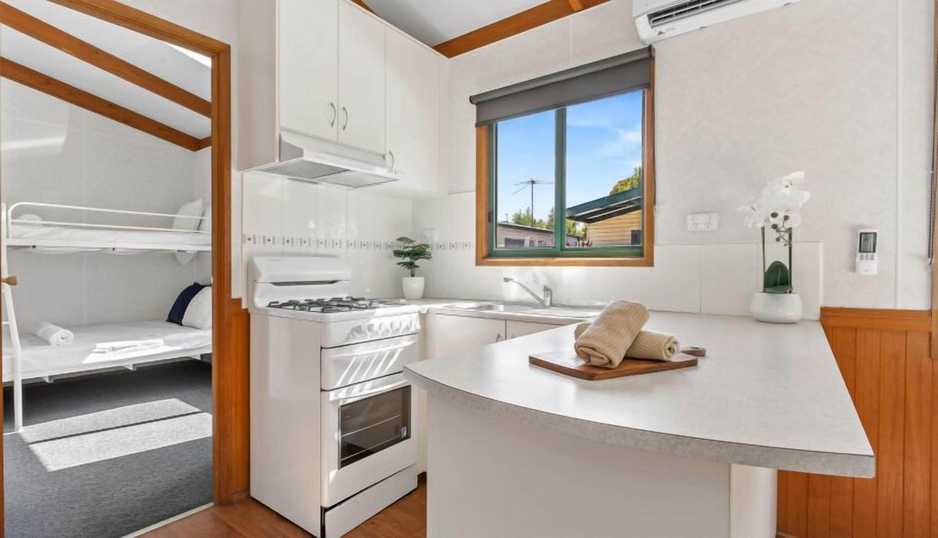 A compact kitchen with a gas stove, oven, and a window with a view of the outside.