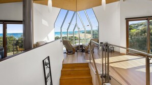 A modern interior with a staircase leading to a balcony with a view of the ocean.