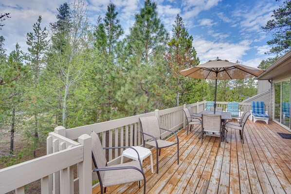 Una terraza de madera con mobiliario exterior, incluyendo sillas y una mesa, y una sombrilla.