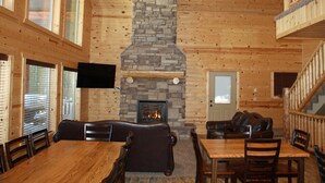 A log cabin interior with a stone fireplace, wooden walls, and a dining area. - Beautiful Cabin In The Trees w/Jacuzzi & Pool Table - 20 Mins From Yellowstone (Island Park)