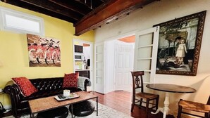 Un salon comprenant un canapé, une table basse et des fauteuils, une table à manger et un tableau accroché au mur.