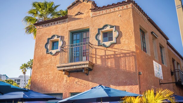 Un bâtiment doté d’une façade à motifs, d’un balcon avec une balustrade et d’une fenêtre ornée d’un cadre décoratif.