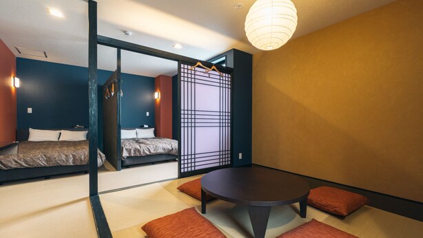 Una habitación moderna con suelo de tatami, una mesa redonda y dos camas.