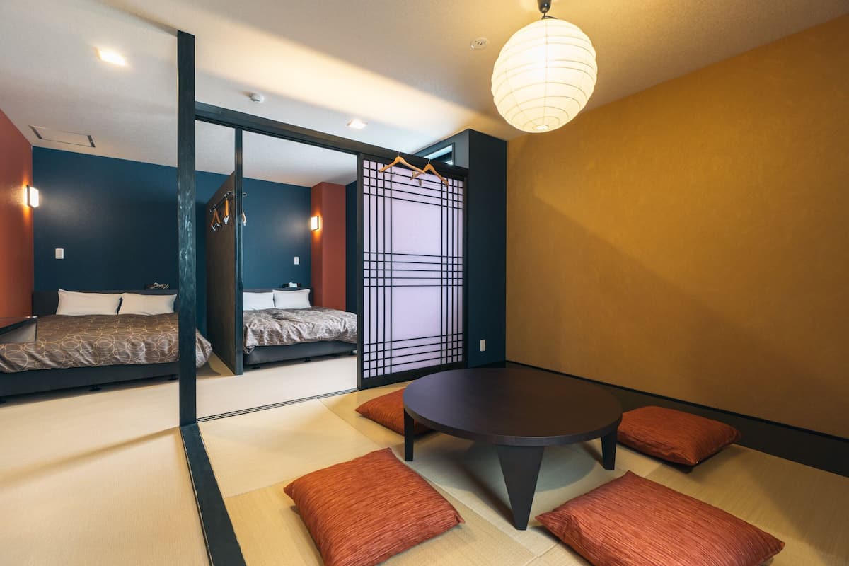 Ein modernes Zimmer mit Tatami-Boden, einem runden Tisch und zwei Betten.