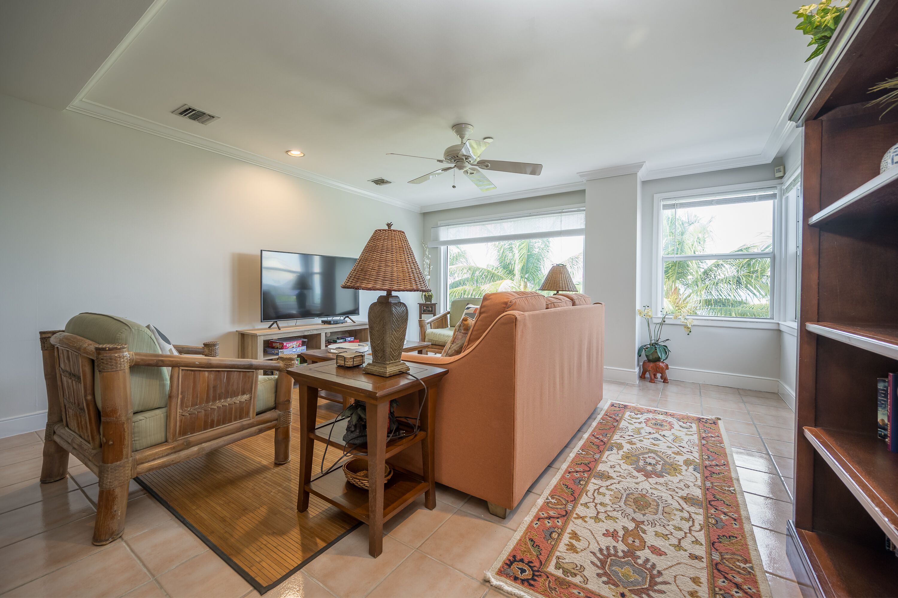 A living room with a sofa, a television, a wooden side table, and a ceiling fan.