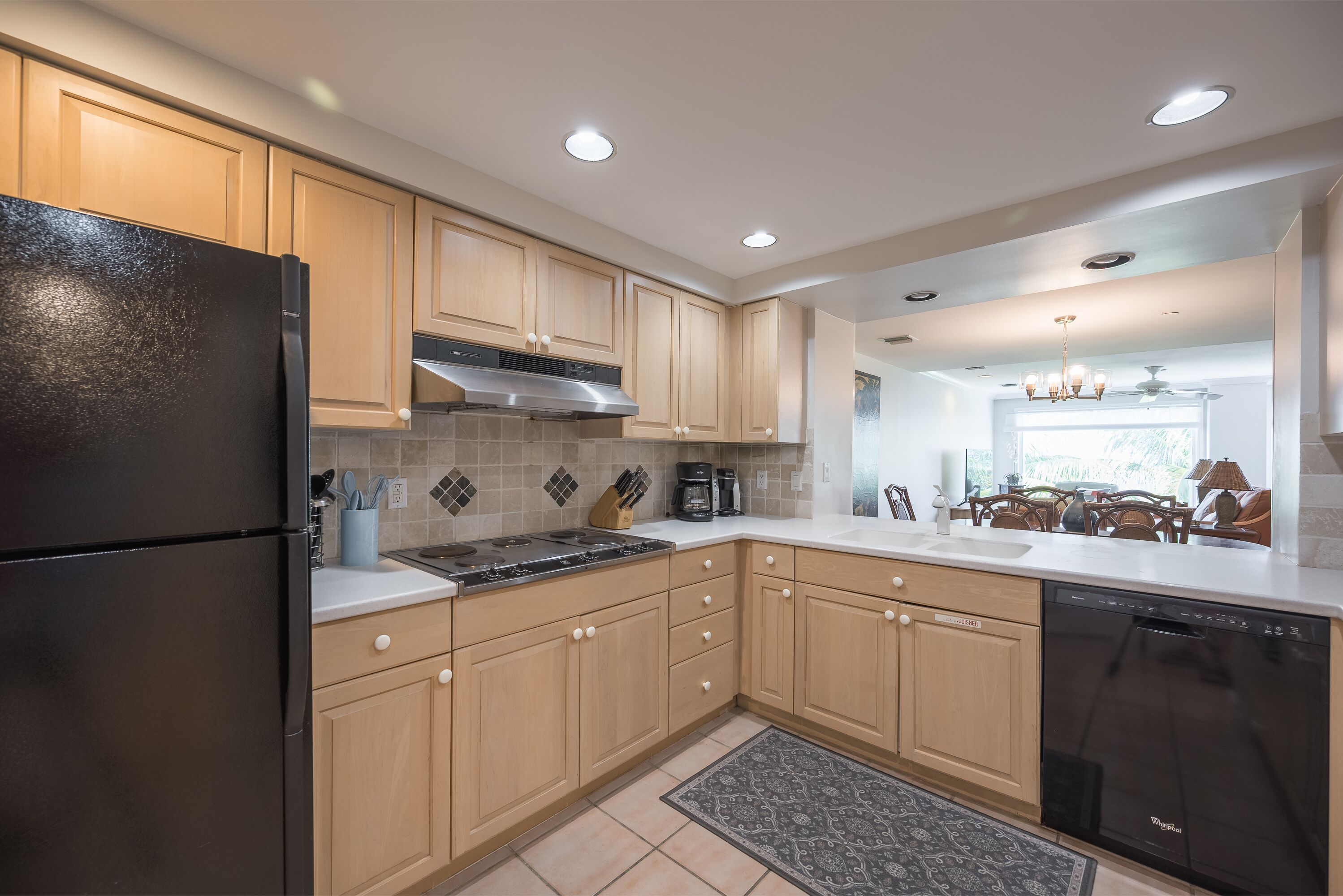 A modern kitchen with wooden cabinets, a black refrigerator, a stove, and a dishwasher.