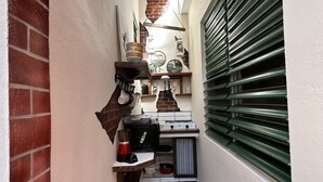 A narrow kitchen with a brick wall, a wooden counter, and a green roller shutter.