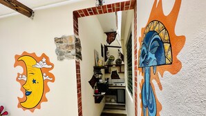 A staircase leading to a kitchen area with a stone wall and a mural of a moon and sun.