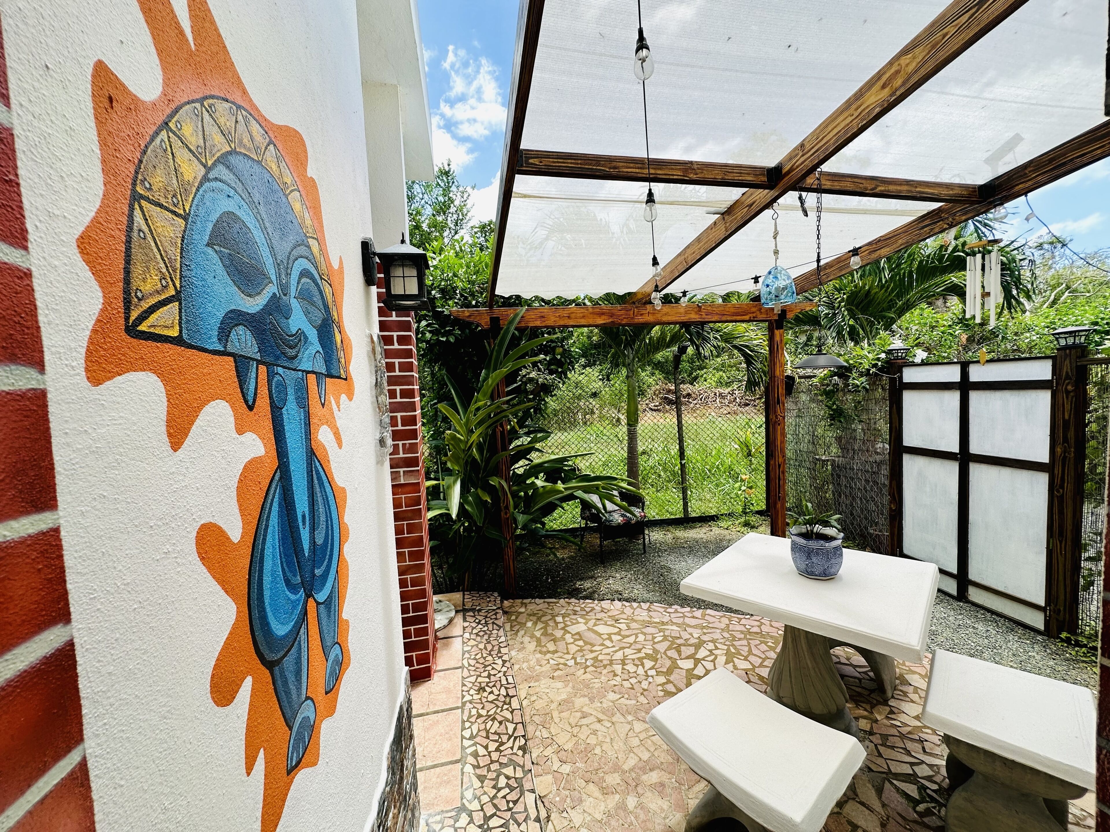 An outdoor patio with a mosaic floor, a table, and benches.
