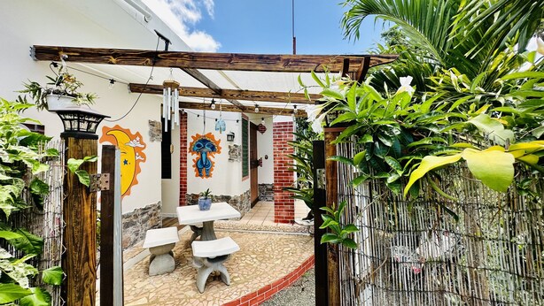 A courtyard with a tiled floor, a wooden pergola, and a mural on the wall.