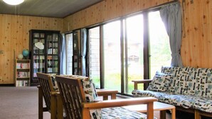 Una habitación con paredes de madera, una amplia estantería, un sofá y una mesa.