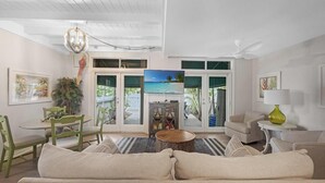 A living room with a sofa, chairs, a coffee table, a TV, and a ceiling fan.