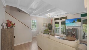 A living room with a sofa, a TV, and a dining area with chairs and a table.