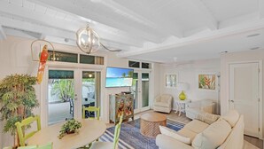A spacious living room with a large TV, comfortable seating, and a view of the outdoors.
