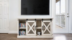 Una TV a schermo piatto montata sopra un mobile in legno con scaffali e una sveglia.