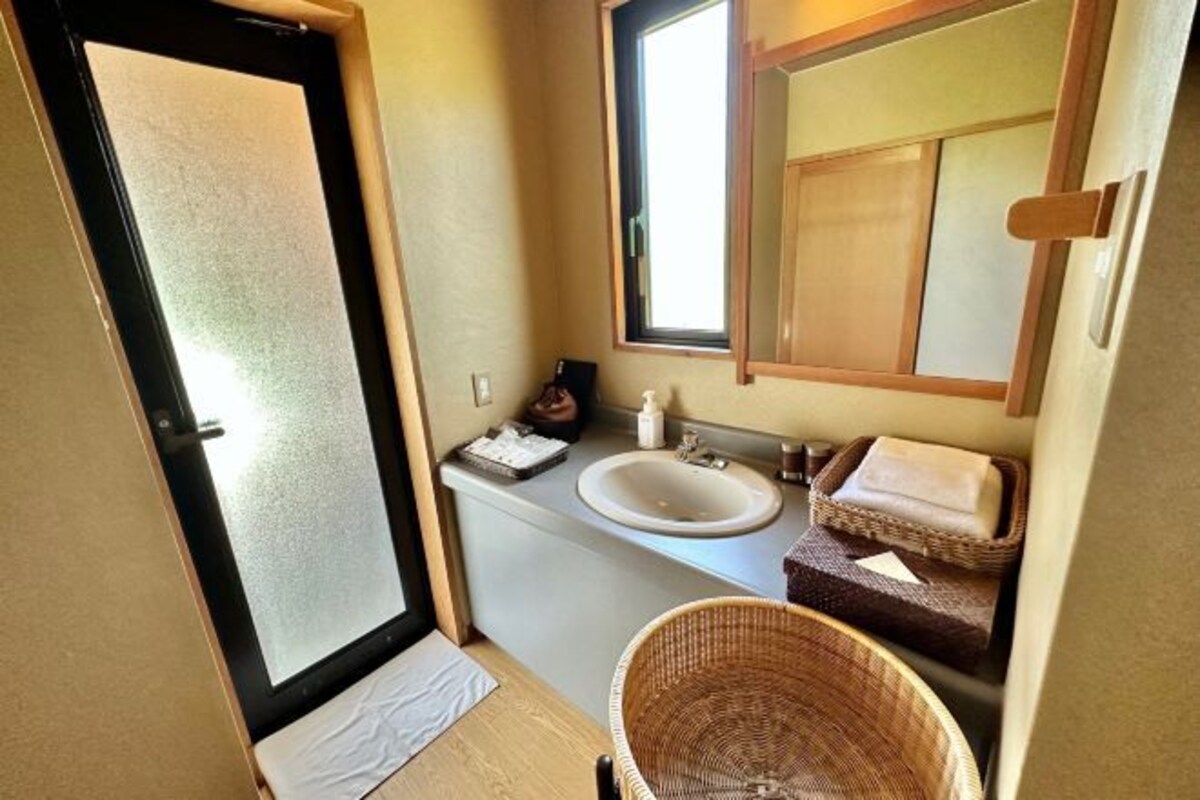 Een kleine badkamer met een wastafel, spiegel en een klein rieten mandje.