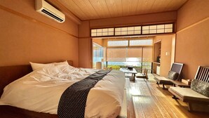 Quarto de hotel com uma cama grande, teto de madeira e vista pela janela.
