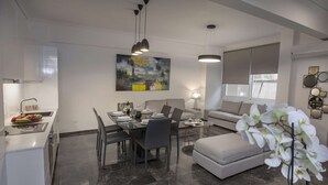 A modern living room with a dining area, a sofa, and a coffee table. - Unique Apartment near Acropolis by GHH (Athens)