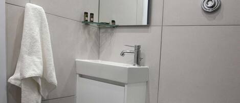 Un baño con inodoro, lavabo, espejo y baldosas de suelo estampadas.