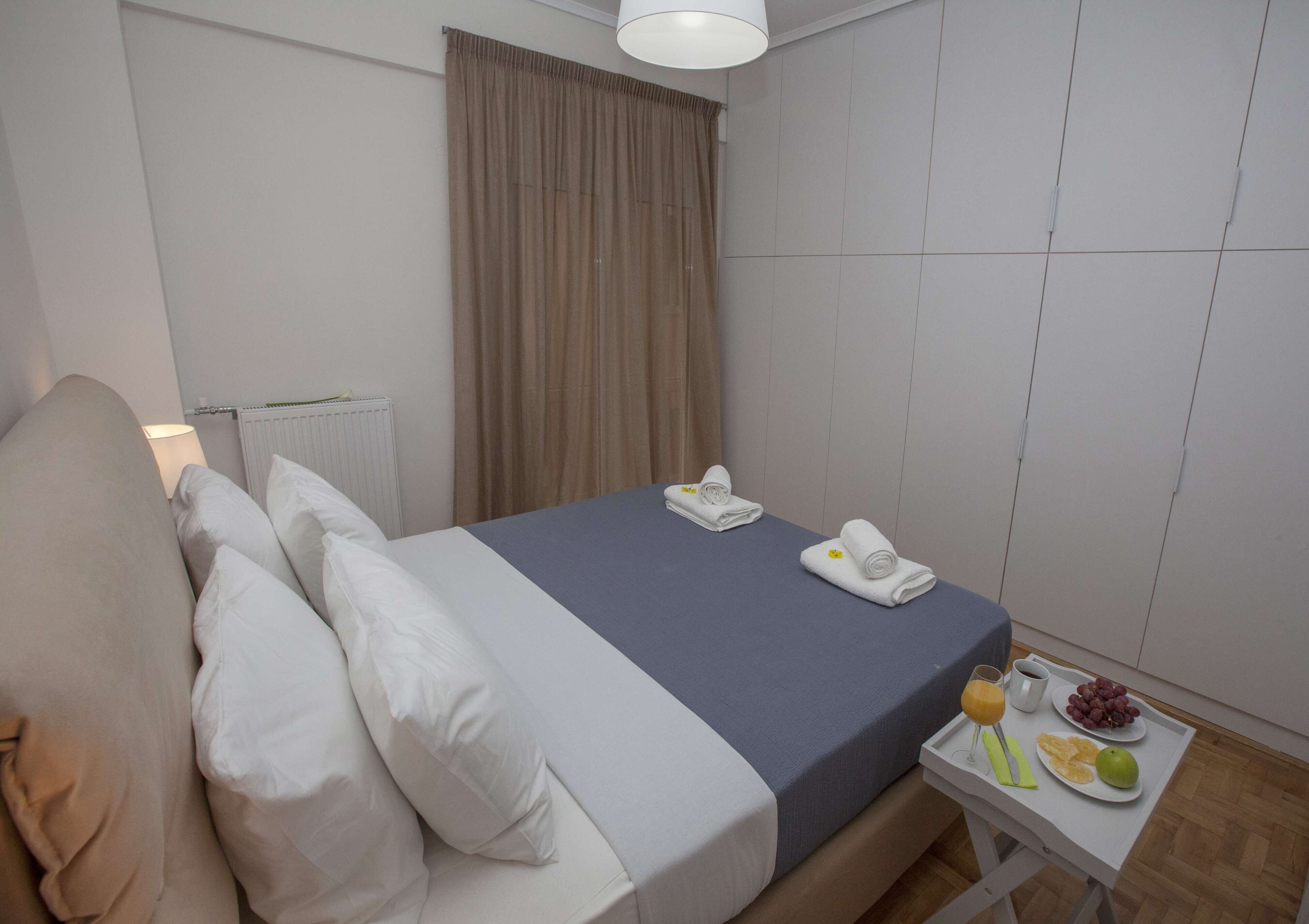 Una camera d'albergo con un letto, un tavolino con prodotti per la colazione e un termosifone.