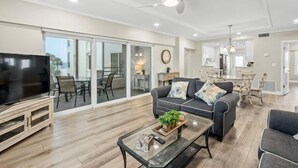 A spacious living room with a large TV, a sofa, and a coffee table. - Island House Beach Resort 14N (Siesta Key)